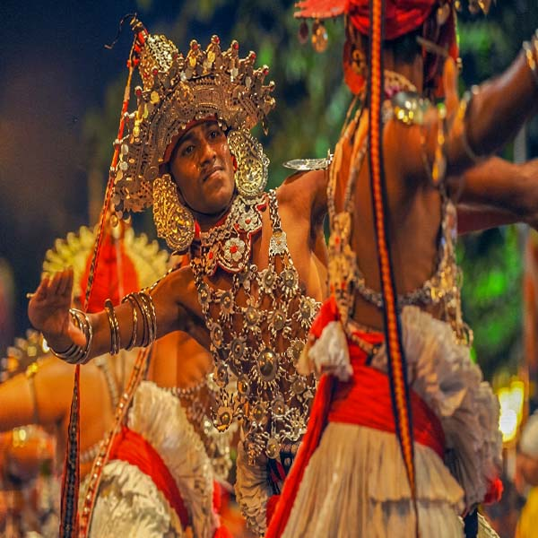 Traditional Kandyan dancer wearing an intricate silver Ves headpiece performing at the Kandy Esala Perahera