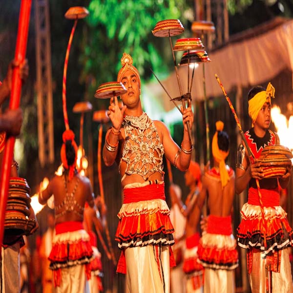 Skilled Kandyan acrobatic dancers balancing spinning rabana drums on long sticks during the Kandy procession
