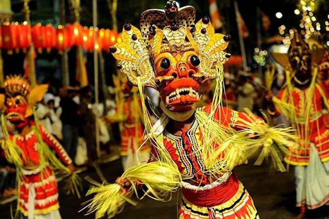 A performer in a traditional mask participating in the Kandy procession