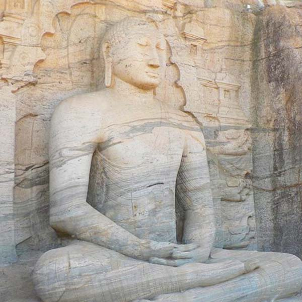 Four massive granite Buddha statues carved into a single rock face at the Gal Vihara temple in Polonnaruwa, Sri Lanka.