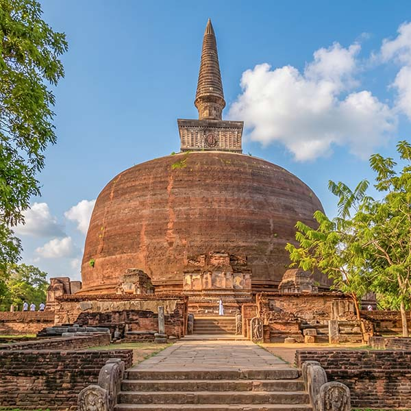 The massive brick dome of the Rankoth Vehera stupa, the largest in the ancient city of Polonnaruwa, with stone pathways leading to the entrance