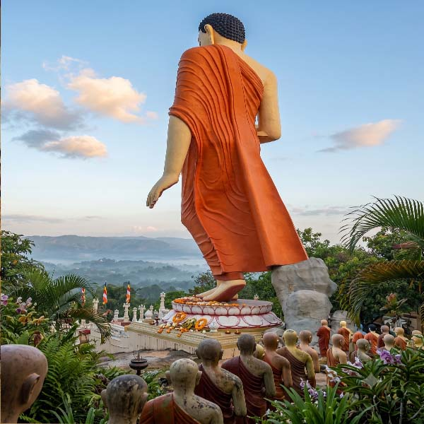A massive walking Buddha statue followed by a procession of monks at the Ranawana Raja Maha Viharaya temple in Kandy.