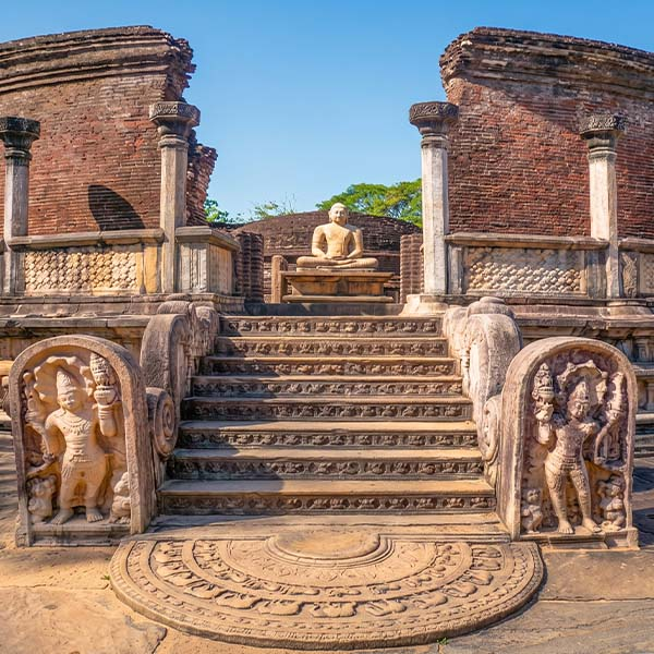 Intricately carved moonstone and stone stairway leading to a seated Buddha statue at the ancient Vatadage in Polonnaruwa.
