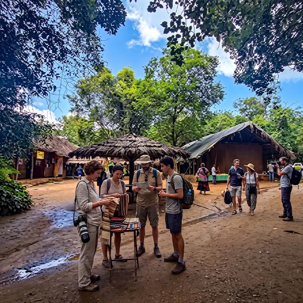 A group of tourists interacting with indigenous locals and exploring traditional crafts at Dambana Vedda Village in Sri Lanka.