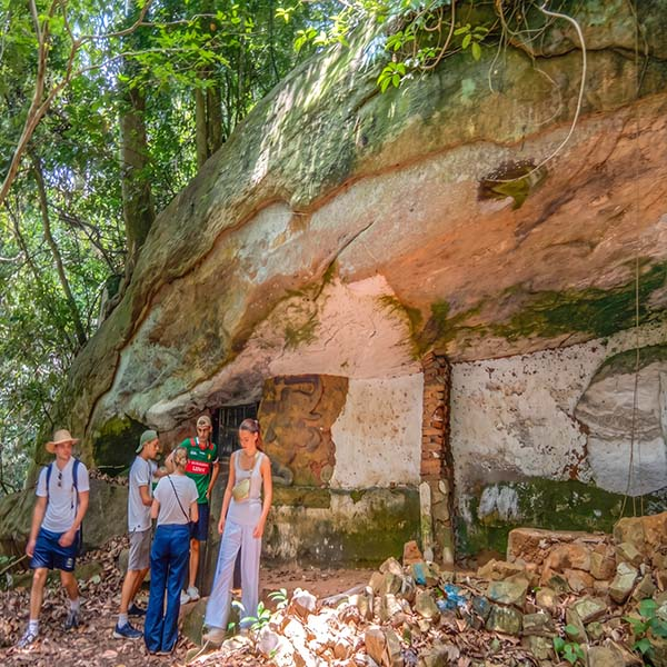 Senkanda Cave in Udawatta Kele: Visitors standing in front of the historic rock shelter, also known as Senkandagala-lena, nestled within Udawatta Kele Sanctuary.