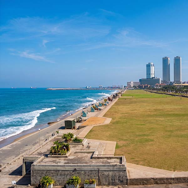 Travelers strolling along the coastline and historic stone fortifications at Galle Face Green in Colombo at sunset