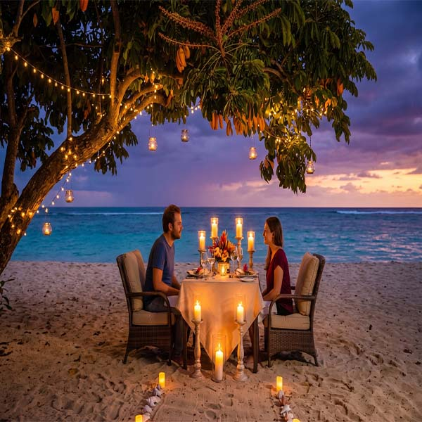 A couple enjoys a private, candlelit seafood dinner at a table set up on a sandy beach at sunset, surrounded by warm lanterns and torches under a twilight sky.