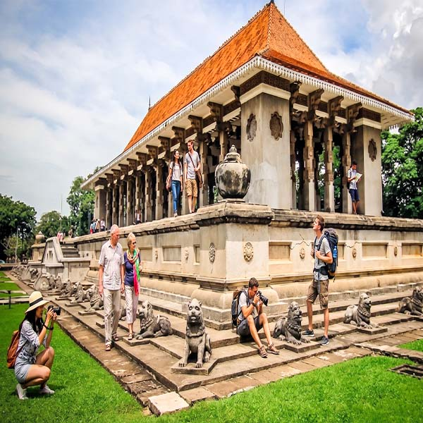Tourists exploring the historic stone pillars and sculptures at Independence Memorial Hall in Cinnamon Gardens during a city tour in Colombo