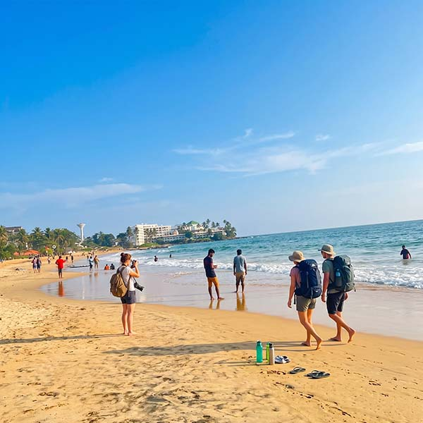 Tourists relaxing and walking along the golden shoreline at Mount Lavinia Beach during a coastal trip in Colombo