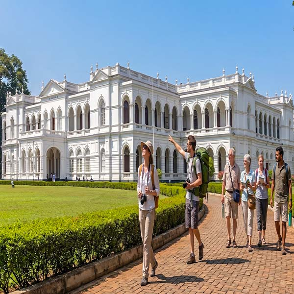 Tourists walking on the lawn in front of the white historic Colombo National Museum building during a city tour