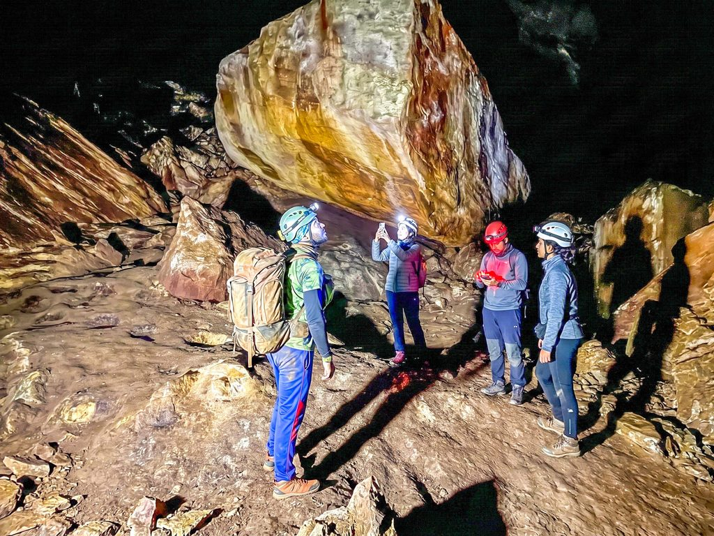 Group of hikers exploring the subterranean rock cavern near the Department of Wildlife Conservation signboard at Nil Diya Pokuna Ella