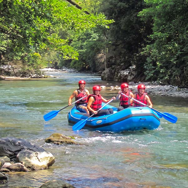 A group of people enjoying white water rafting in a bright blue and red raft on the scenic Kelani River in Kitulgala, Sri Lanka.