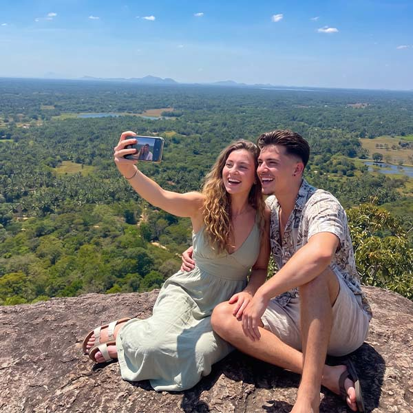 Couple taking a selfie with a scenic view over the surrounding plains from the summit of Yapahuwa Rock Fortress in Sri Lanka