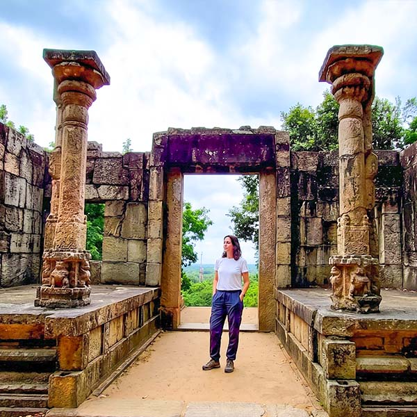 Solo traveler standing between carved stone pillars and ruins at the summit