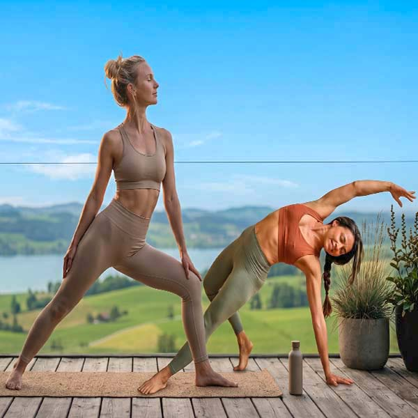 Two women stretching on a balcony overlooking the hills.