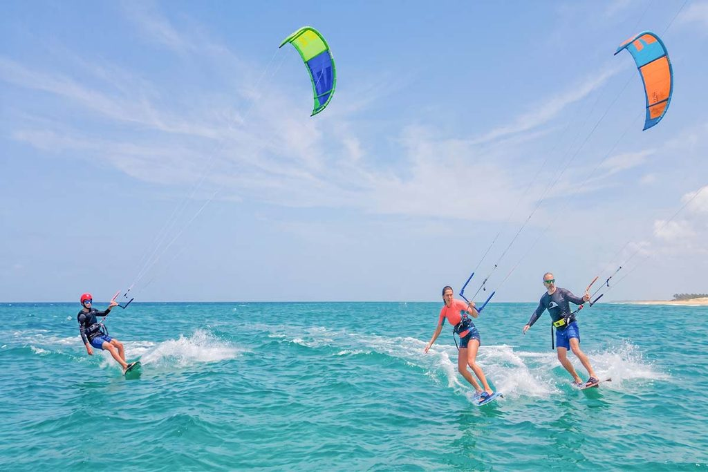 Kite surfers riding the waves and practicing in the water off the Kalpitis coast under a clear blue sky