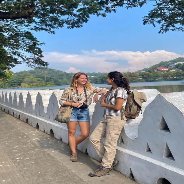 Two travelers enjoying the scenic view of Kandy City Lake during their 7-day Sri Lanka tour package