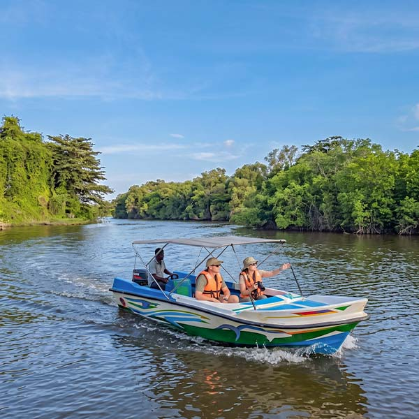 Travelers enjoying a scenic boat tour on the Kala Oya river, passing through lush mangrove forests and waterways in Gange Wadiya, Sri Lanka.