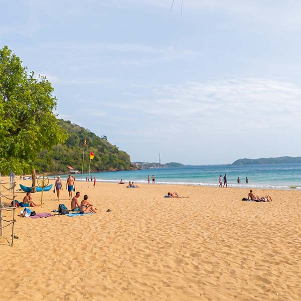 Travelers relaxing on the white sands and shallow turquoise waters of Nilaveli Beach during a northern tour.