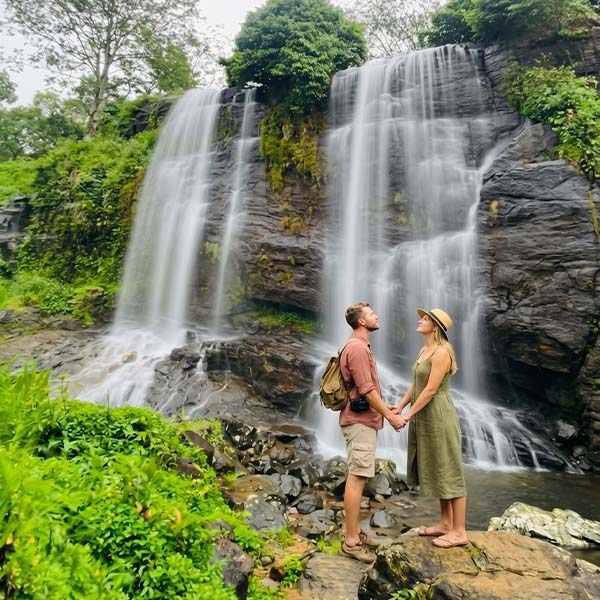 Two travelers photographing Jodu Ella twin waterfalls during a Kandy day tour.