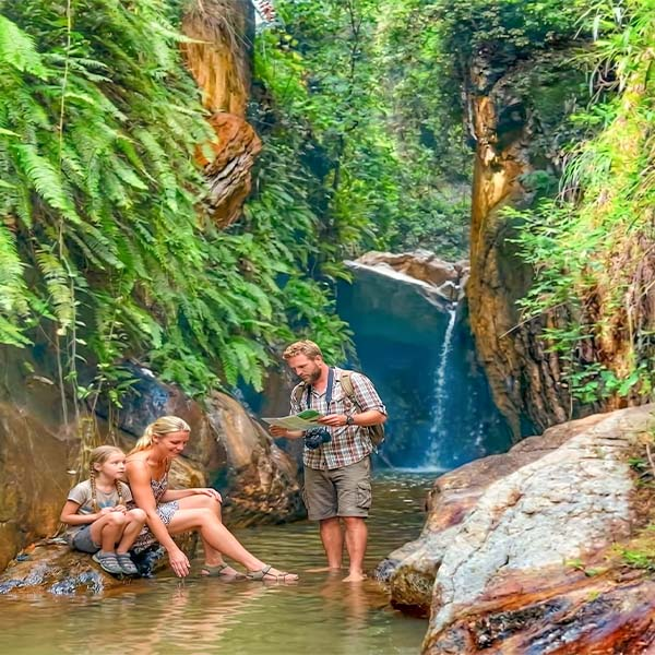 Two travelers relaxing by the pool at Ras Ella waterfall during a Kandy day tour.